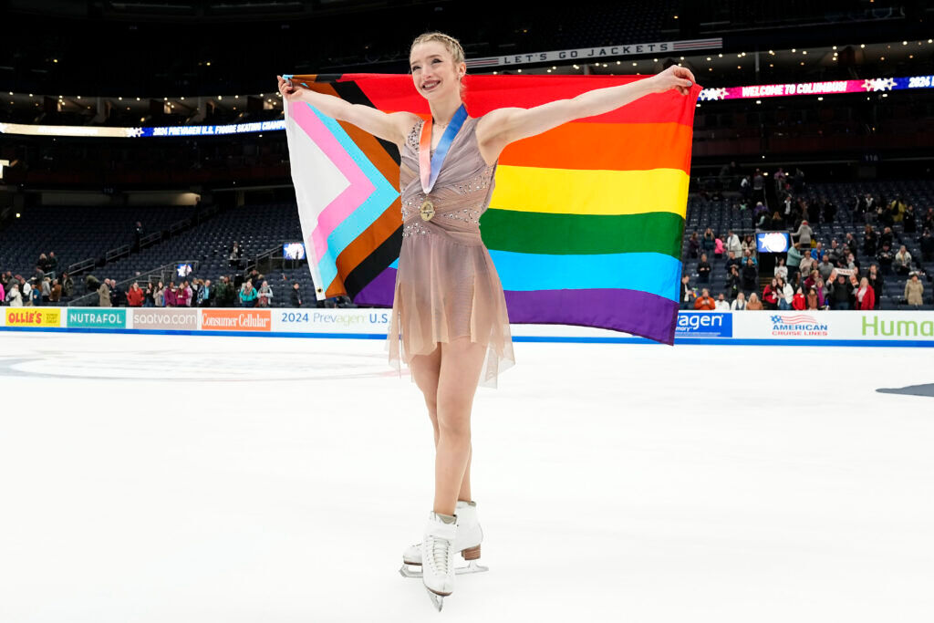 Amber Glenn poses with the Progress Pride flag.