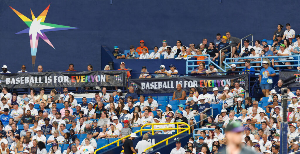 A rainbow logo on the stadium wall during a baseball game