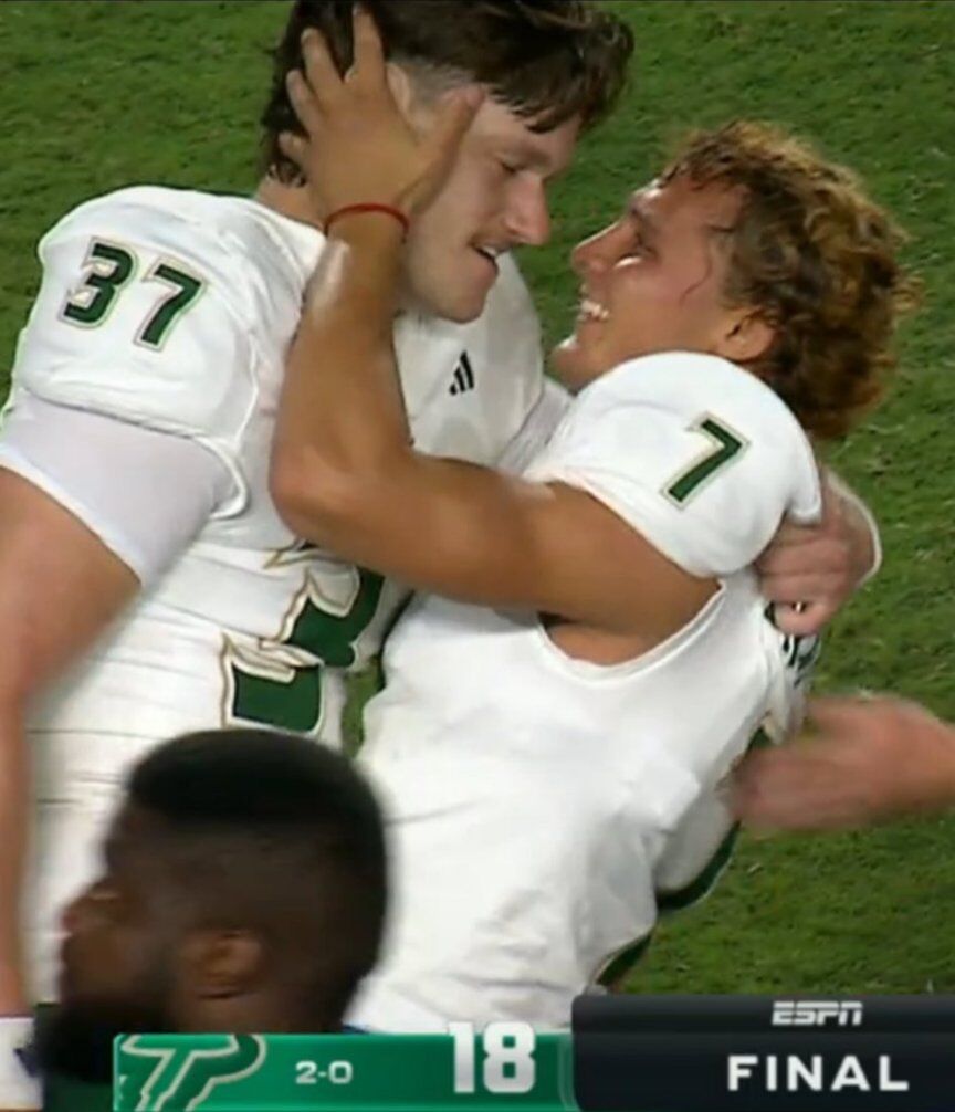 College football players embrace and look into each other's eyes after a win.